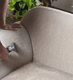 Professional upholstery cleaner deep-cleaning a fabric sofa with a handheld extraction tool and hose Hollywood, FL.